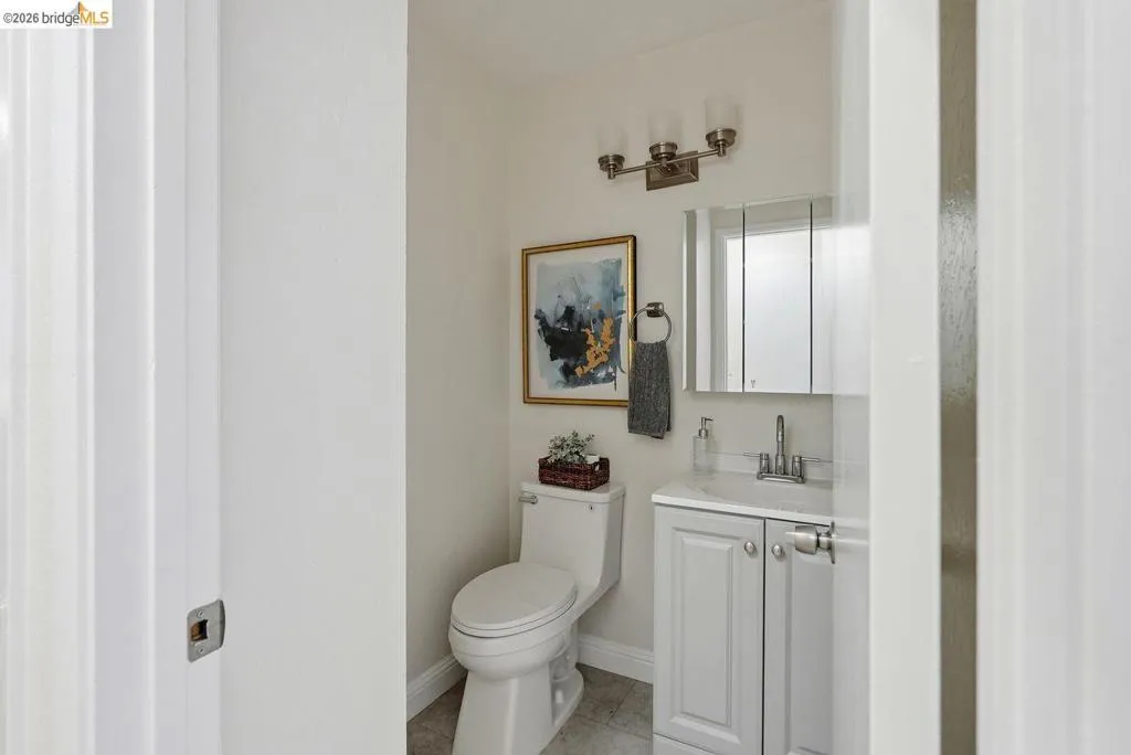 Bathroom featuring a white toilet, light gray vanity with chrome hardware, an integrated sink, and a mirrored medicine cabinet