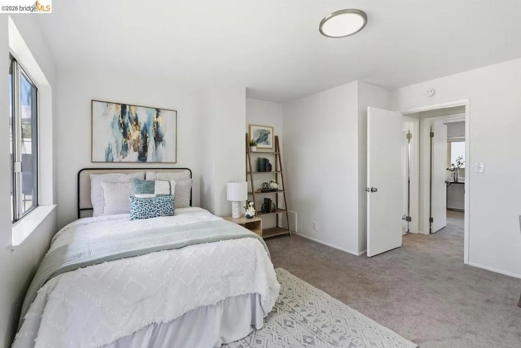 Bedroom featuring light-colored carpeting, white walls, and a large window