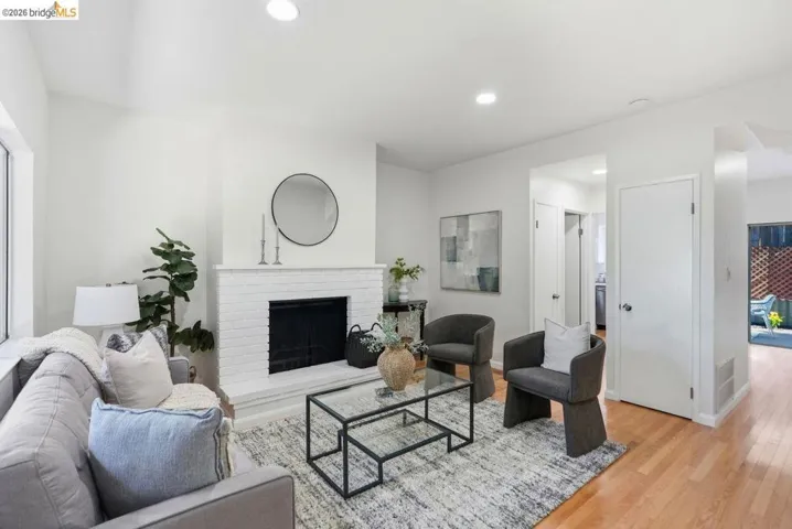 Bright living area with a white brick fireplace, recessed lighting, and wood-finish flooring