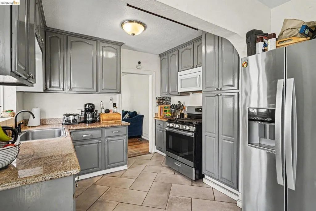 Kitchen featuring gray cabinetry, granite-finish countertops, and stainless steel appliances