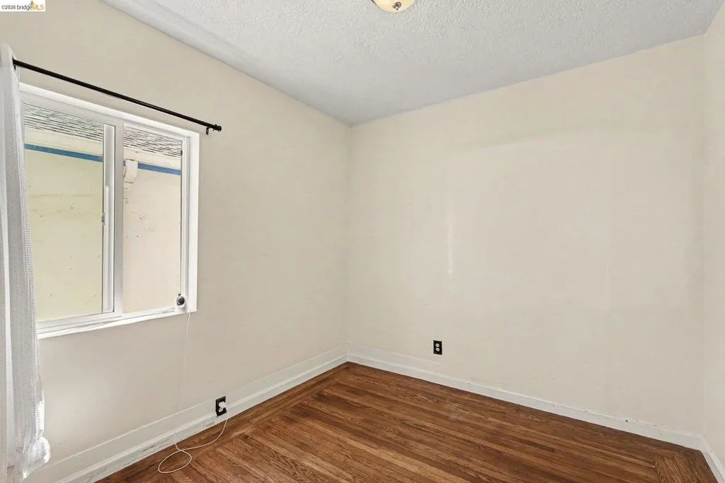 Room featuring wood-finish flooring, light-toned walls, and a white-framed window