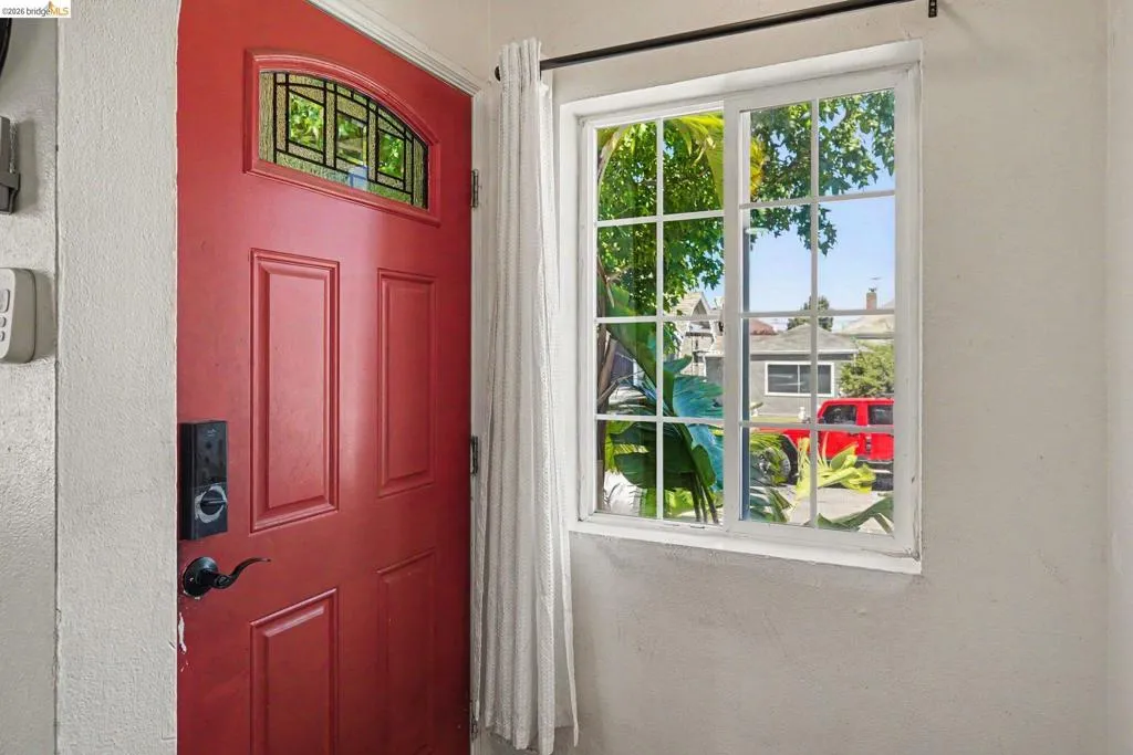 Red paneled entry door with an arched transom window featuring decorative grilles