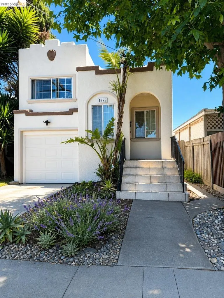 Stucco exterior with arched entry, contrasting trim accents, and an integrated garage