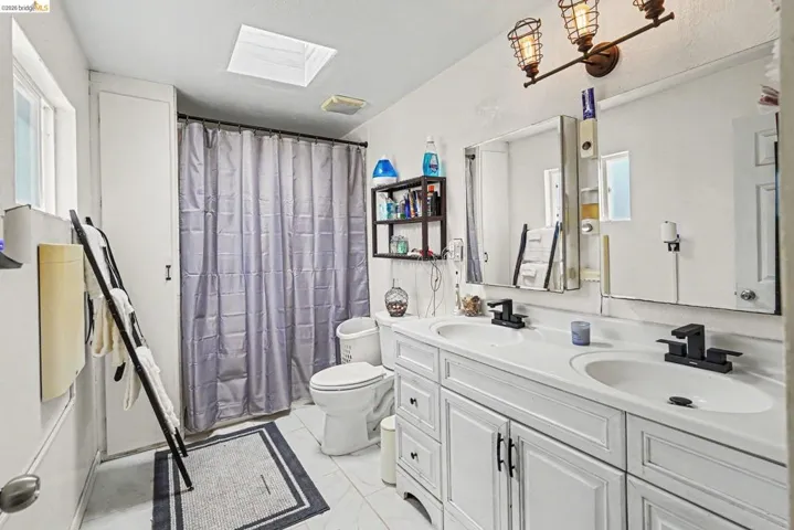 Bathroom featuring a dual vanity with white cabinetry, black hardware, and integrated sinks