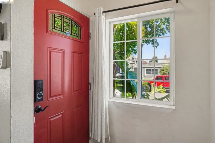 Red paneled entry door with an arched transom window featuring decorative grilles