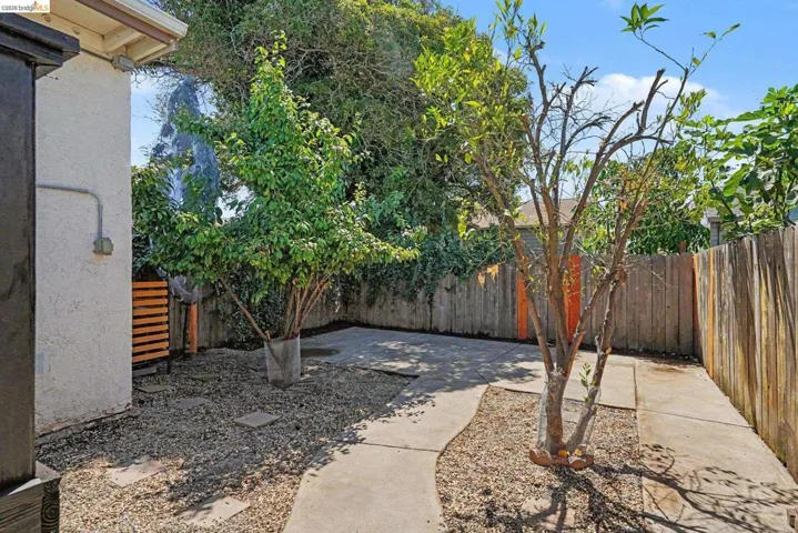 Private outdoor space featuring concrete pathways, gravel landscaping, and mature trees