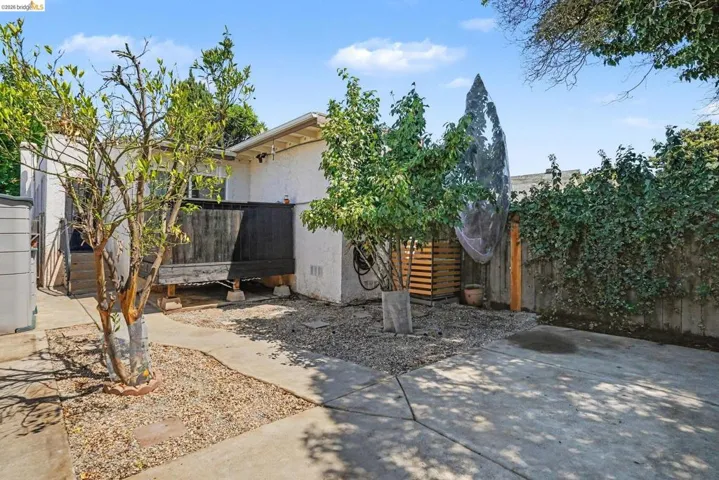 Concrete patio area with gravel accents and mature trees