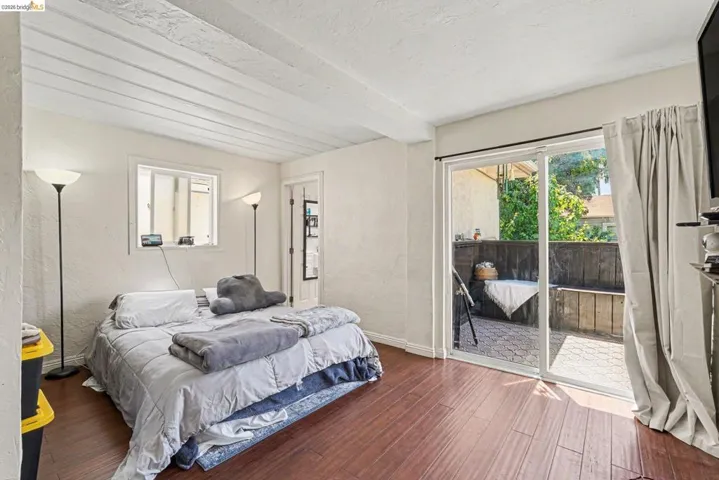 Interior space featuring wood-finish flooring and a white textured ceiling with exposed beams