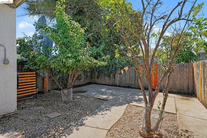 Private outdoor space featuring concrete paving, gravel landscaping, and established trees