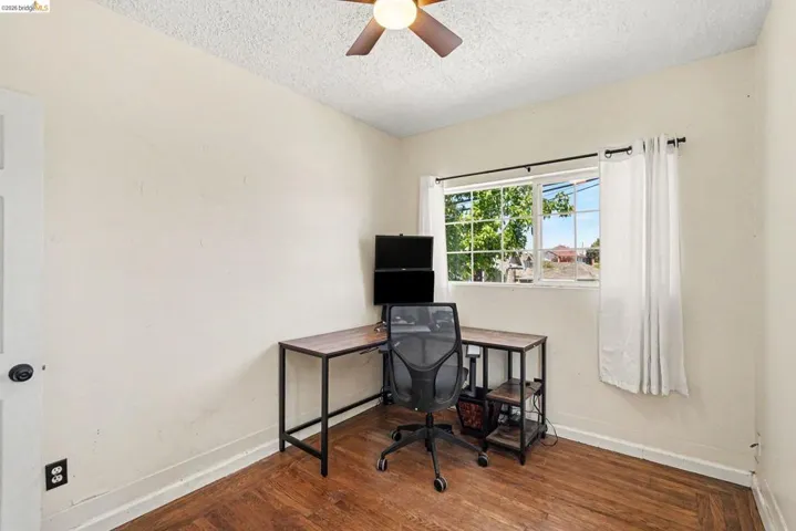Room with wood-finish flooring, a ceiling fan, and a window with a white frame