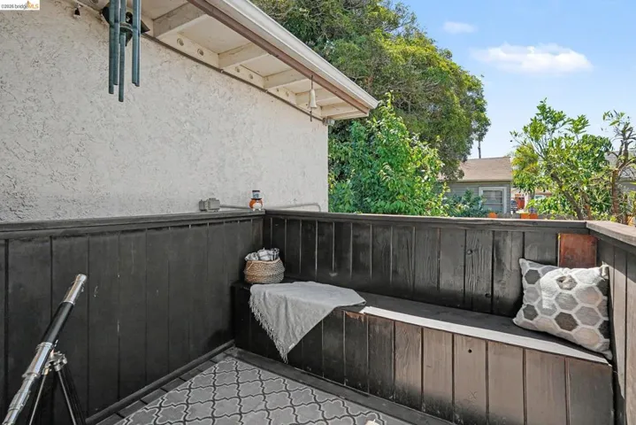 Outdoor patio featuring a built-in bench, dark wood-paneled walls, and a patterned outdoor rug