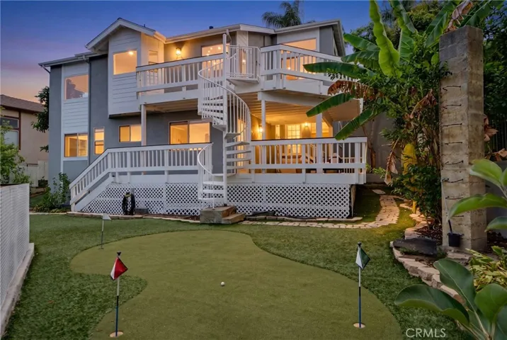 Hillside View home with multiple. entertainment decks, putting green, and great yard with fruit trees and natural plants.  Photo was "twilight enhanced"