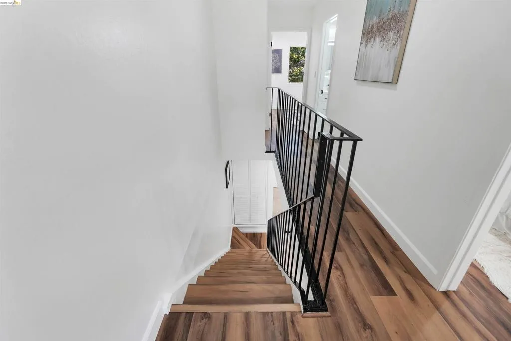 Staircase featuring wood-finish treads and risers, complemented by a black metal railing