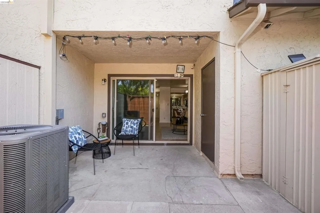 Covered patio featuring concrete flooring, a sliding glass door, and an exterior door