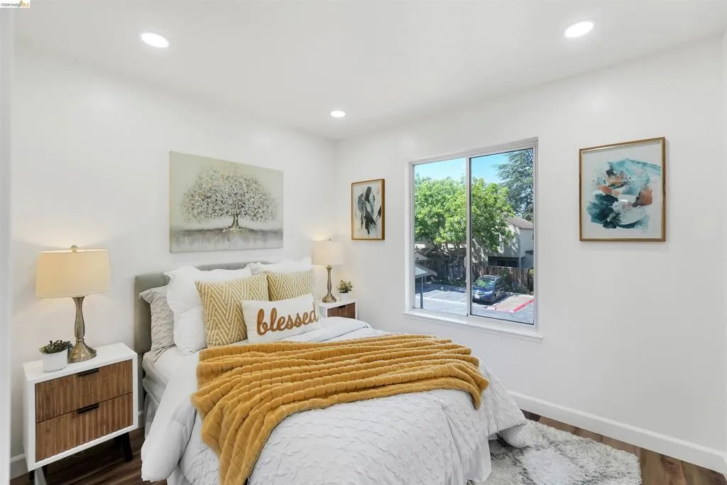 Bright room featuring white walls, recessed ceiling lighting, a large window, and wood-finish flooring