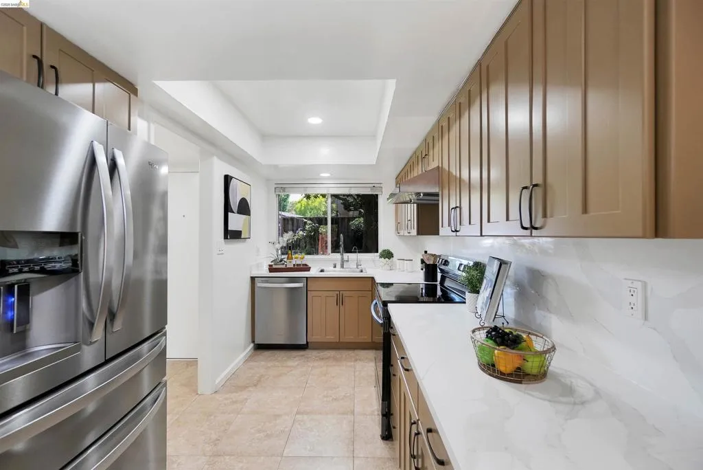 Contemporary kitchen featuring stainless steel appliances, stone countertops, and tile flooring