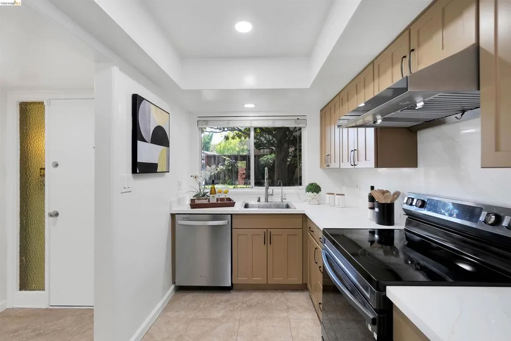 Galley kitchen featuring light-toned cabinetry, white countertops, and a white tile backsplash