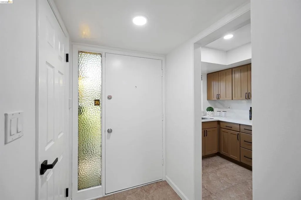 Entryway featuring a solid white door with a textured glass sidelight, tile flooring, and recessed lighting
