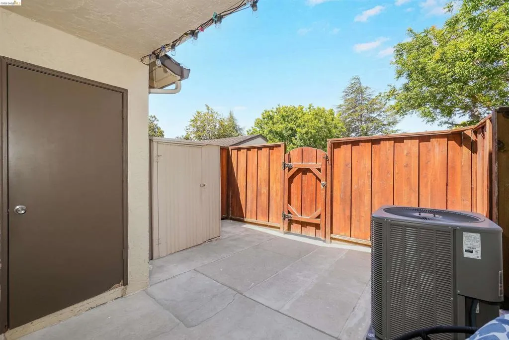 Private outdoor patio featuring a concrete slab, a secure brown wooden fence, and a wooden gate
