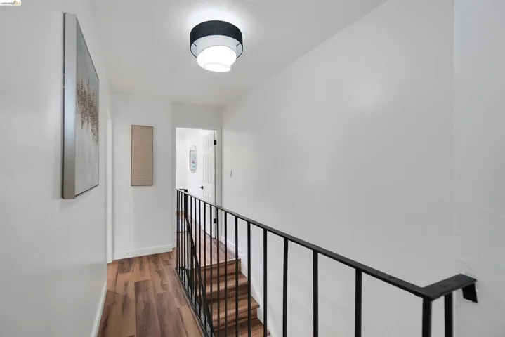 Hallway with wood-finish flooring, white walls, and a modern flush-mount ceiling light