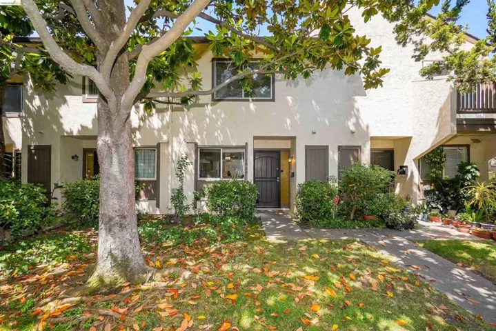 Cream stucco exterior with brown trim accents and a dark entry door