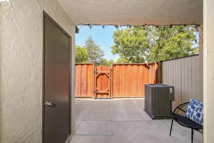 Outdoor patio space featuring a concrete slab, a wood privacy fence, and a wood gate