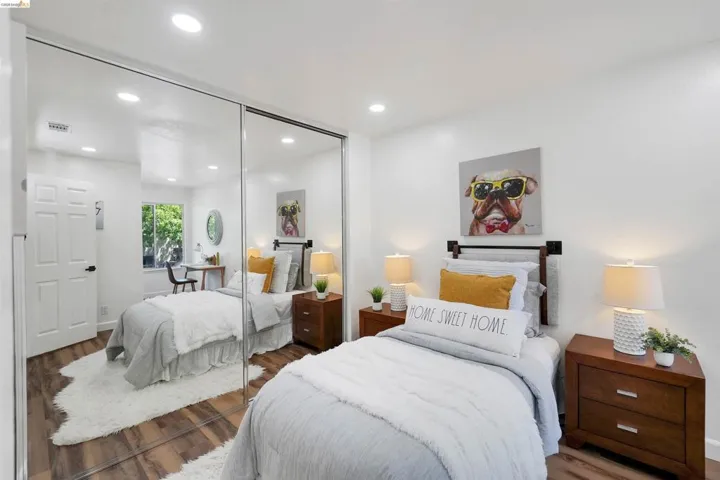 Bedroom featuring wood-finish flooring, recessed lighting, and a full-wall mirrored closet
