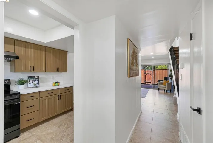 Tiled entryway leading to a kitchen with wood-finish cabinetry, white countertops, and a white tile backsplash