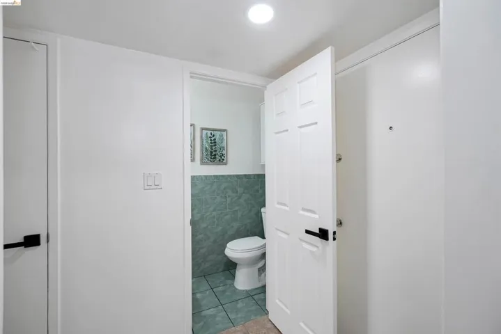 Compact bathroom featuring a white toilet, green tiled walls, and coordinating green floor tiles