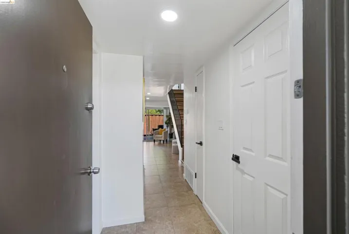 Inviting entry with tile flooring, recessed lighting, white paneled interior doors, and a wood-finish staircase