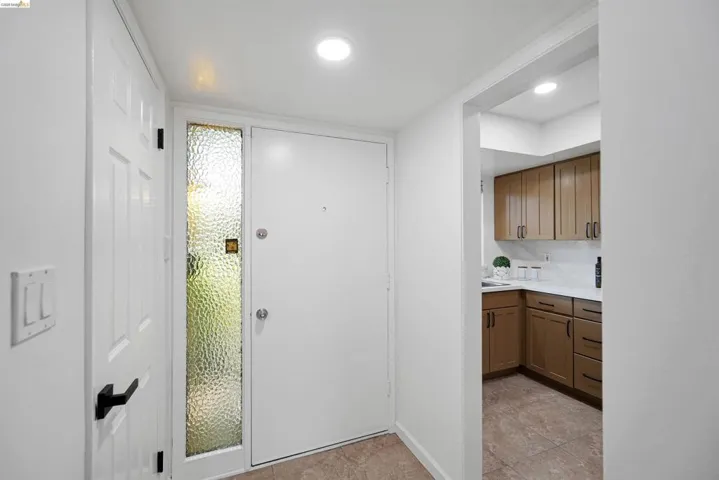 Entryway featuring a solid white door with a textured glass sidelight, tile flooring, and recessed lighting