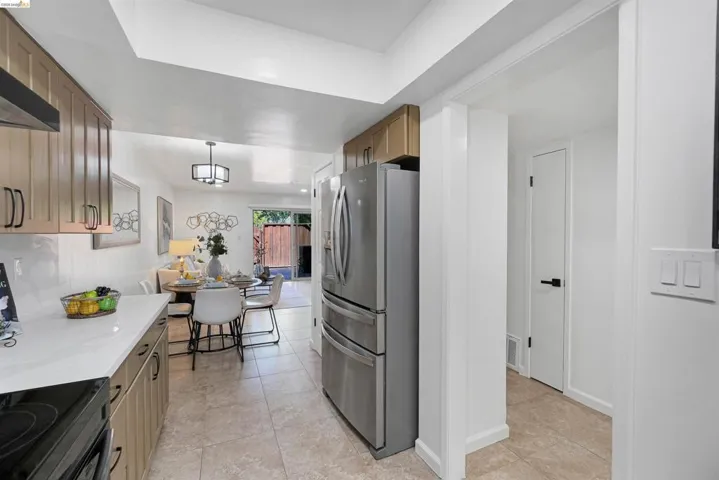 Contemporary kitchen featuring light wood-finish cabinetry, stainless steel appliances, a white countertop, and tiled flooring