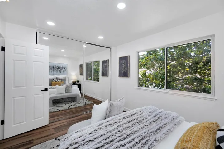 Bedroom featuring a window with abundant natural light, wood-finish flooring, recessed lighting, and mirrored closet doors