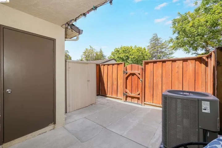 Private outdoor patio featuring a concrete slab, a secure brown wooden fence, and a wooden gate