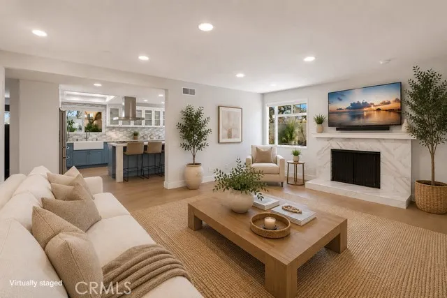 Spacious living room with fireplace opens to kitchen.
Virtually staged.