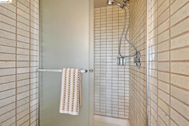 Shower enclosure featuring subway tile walls, a handheld shower fixture, and a built-in soap niche