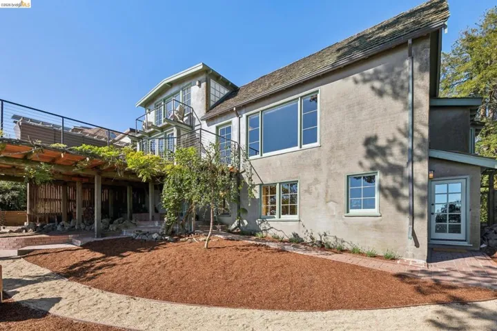 Multi-level exterior featuring stucco siding, varied window styles, and a large wood deck with cable railings