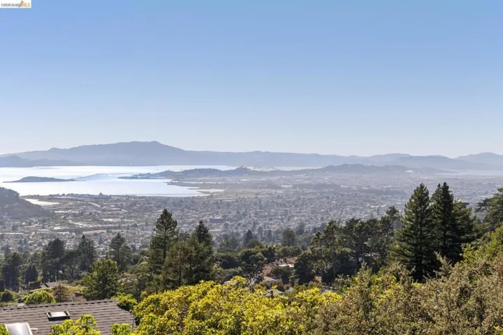 Expansive water and city scape featuring distant mountains and a densely treed foreground
