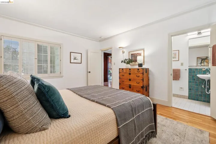 Bedroom featuring wood-finish flooring, white walls, and a multi-pane window with louvered blinds