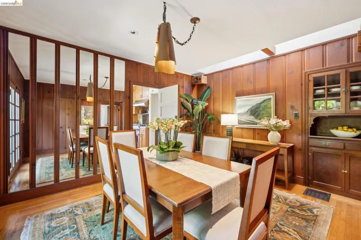 Paneled dining area featuring wood-finish flooring, a built-in china cabinet, and a mirrored wall partition