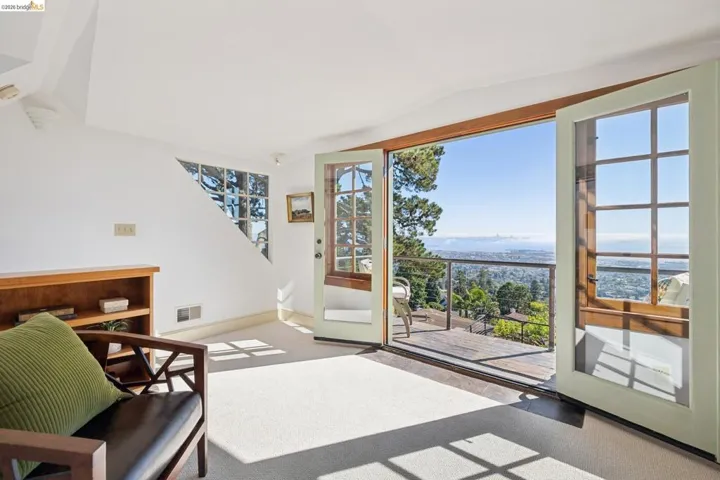French doors opening to an outdoor deck with distant city and bay scenery