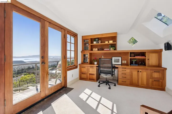 Room featuring extensive built-in wooden cabinetry with varied storage options, a large skylight, and expansive glass doors opening to an exterior balcony