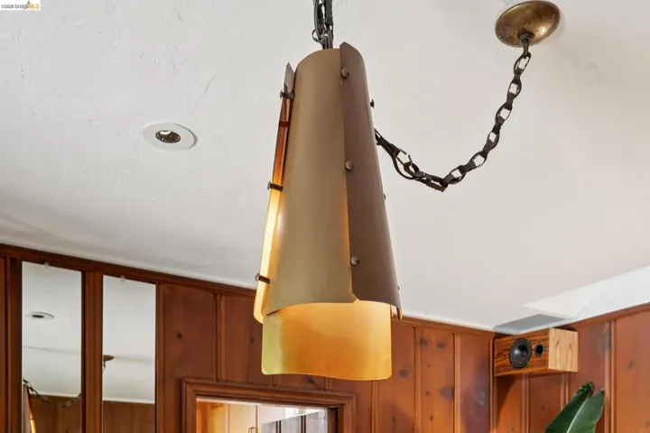 Ceiling-mounted pendant light fixture with a metallic chain and decorative shade