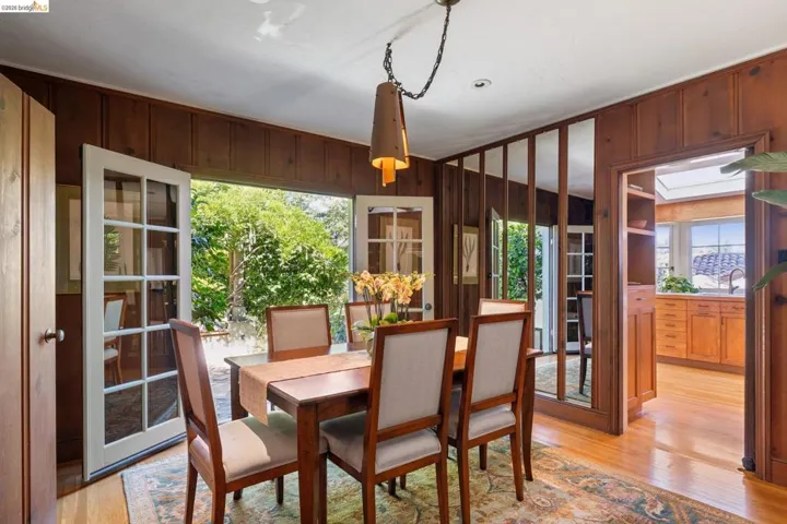 Dining area featuring wood paneled walls, hardwood flooring, and a decorative pendant light fixture