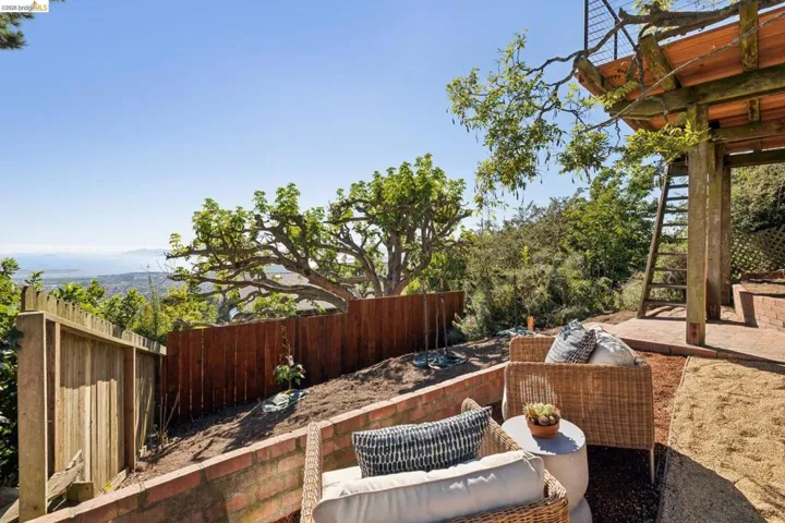 Terraced outdoor area featuring brick retaining walls, a wood fence, and a dedicated patio space
