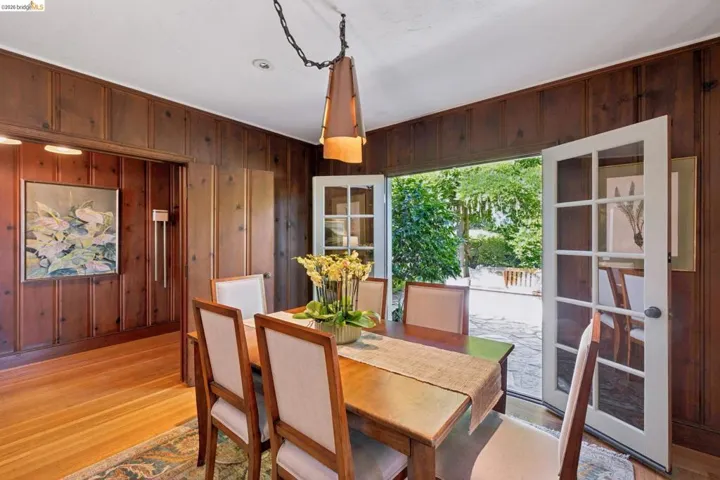 Dining area featuring wood-finish wall paneling, hardwood flooring, and a contemporary pendant light fixture