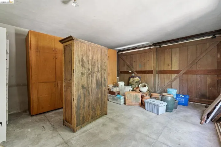 Concrete flooring, wood plank paneled wall, and built-in wood cabinetry