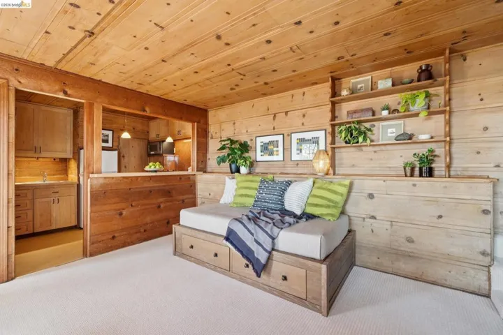 Wood-paneled room featuring a built-in shelving unit and a pass-through opening to a kitchenette