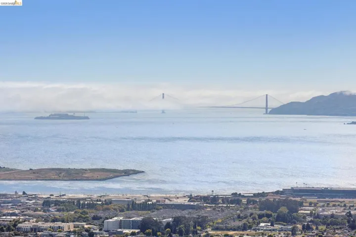 Expansive water frontage showcasing a prominent suspension bridge, distant island, and city skyline