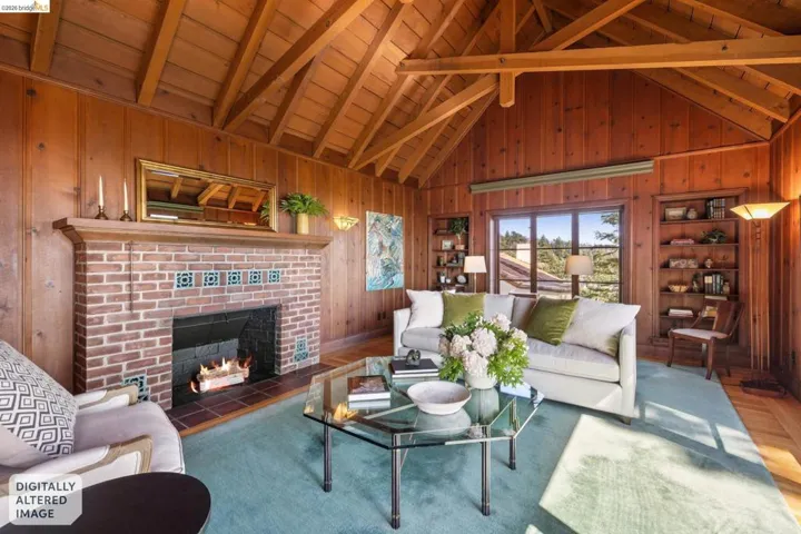Spacious living area featuring extensive wood paneling, an exposed beam vaulted ceiling, large picture windows with Bay views, built-in shelving, fireplace and hardwood floors.